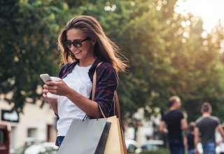Young woman texting while enjoying a day shopping Wallpaper