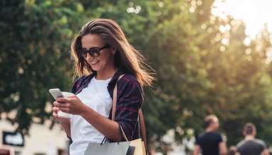 Young woman texting while enjoying a day shopping Wallpaper