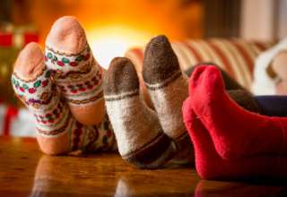 Close-up photo of family feet in wool socks at fireplace